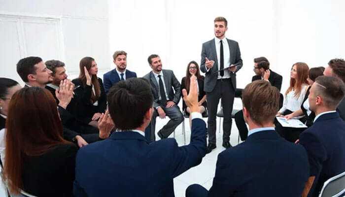 Business persons in formal attire undertaking a group discussion on payroll management across borders.