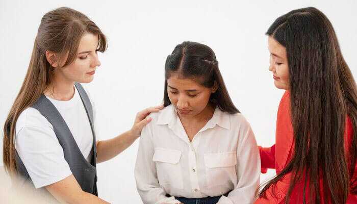 Three women in a supportive setting, addressing concerns about workplace sexual assault with empathy and understanding.