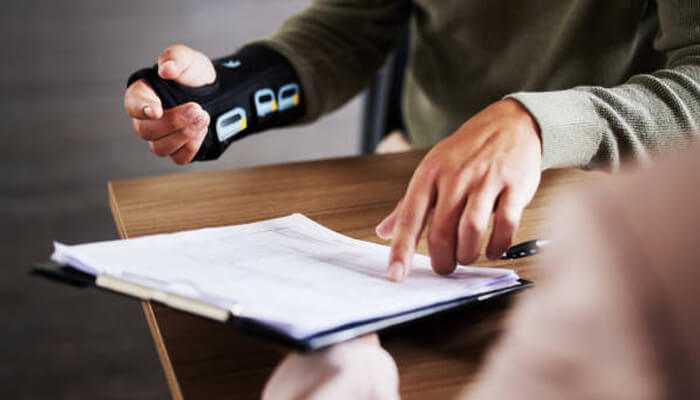 Workplace injuries | tycoonstory media A person with a hand injury pointing at legal documents, indicating personal injury claims.