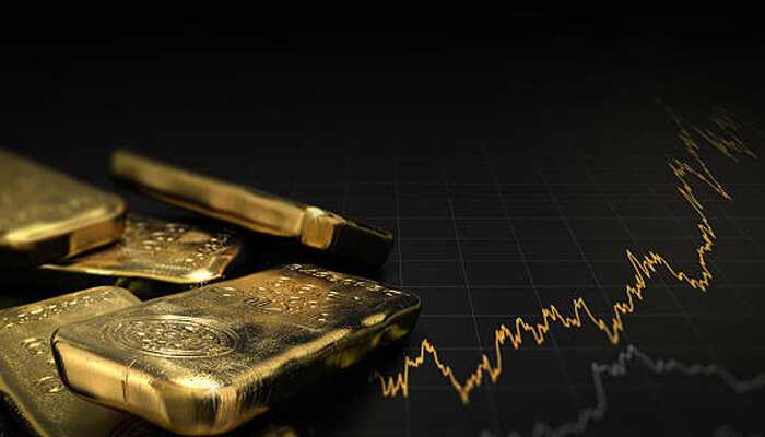 Close-up of stacked gold bars with a financial market graph in the background, representing investing in gold.