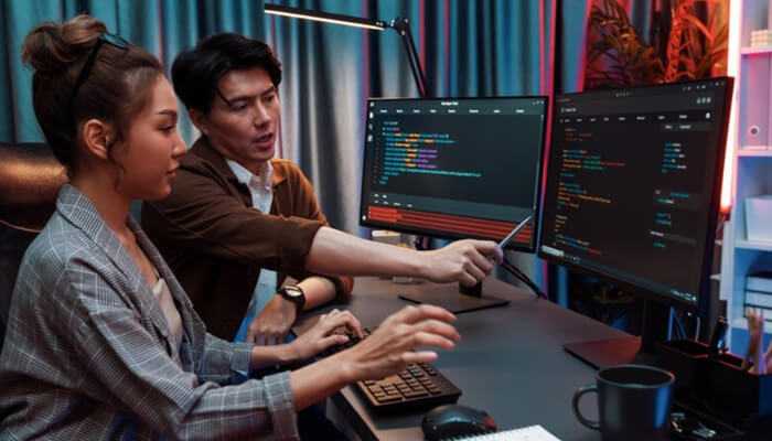 Team collaboration in a coding session, showing why companies hire full stack developers to manage complex software development tasks.