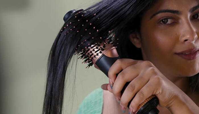 Using a hair dryer brush to smooth and style hair, ensuring a sleek and polished look.