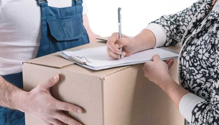 Customer signing delivery receipt during preshipment process with courier holding a package