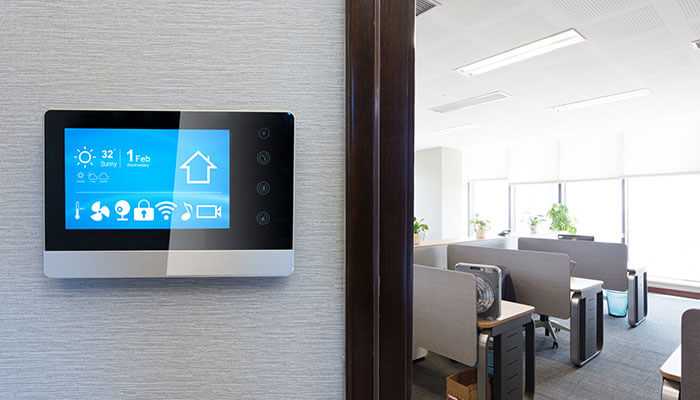 Smart thermostat on the wall of a bright, energy-efficient office, highlighting the use of technology in office renovations.