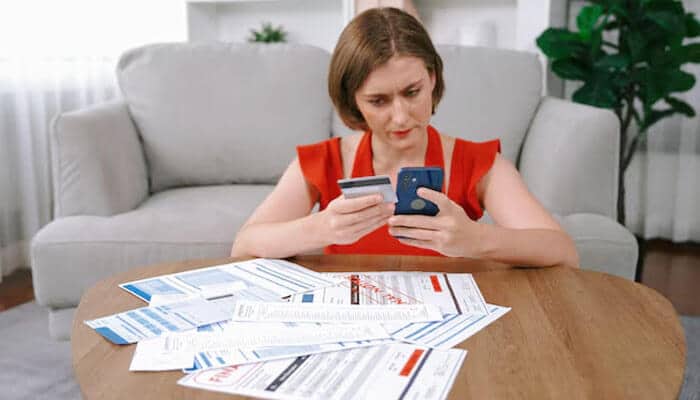 A woman comparing credit card statements and managing expenses at home, representing financial stress relief and debt management through a personal loan for salaried professionals.