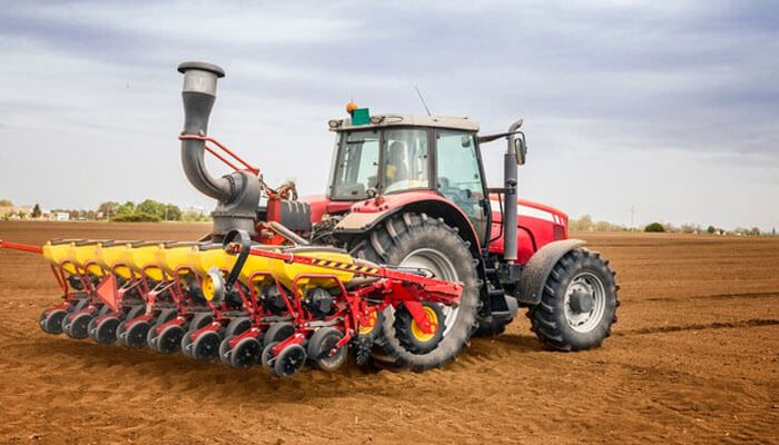 Modern red tractor with seed drill tractor implements preparing soil for sowing.