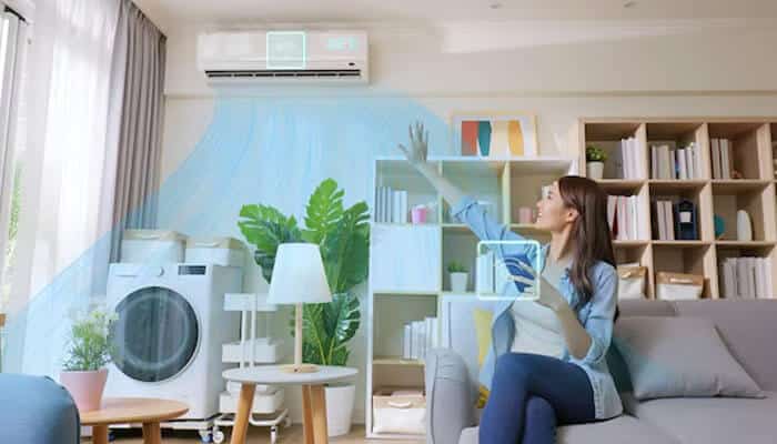 Woman using a smart air conditioning unit inside a modern living space, illustrating comfort and energy efficiency powered by a commercial hvac system.