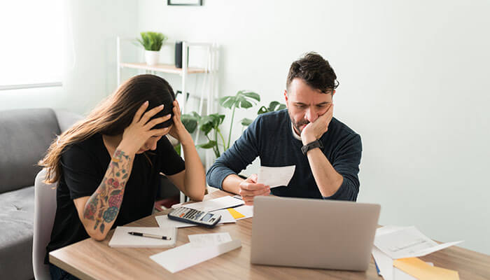Stressed couple reviewing bills and paperwork, highlighting the strain financial infidelity places on trust and communication.