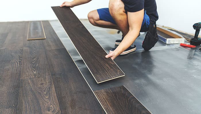 Professional installing durable commercial floors with dark wood finish, emphasizing strength and long-lasting performance.