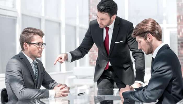 Resolving business disputes - tycoonstory | tycoonstory media Business law attorney mediating a discussion between clients during a legal consultation meeting.