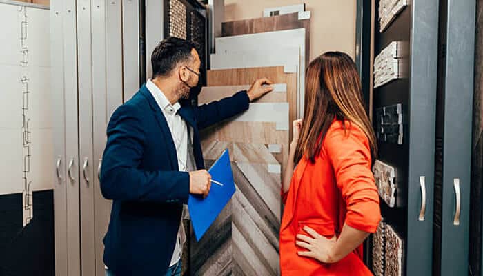 A salesperson showing a customer various tile samples in a showroom, highlighting the process of comparing materials to find the best floor tiles.