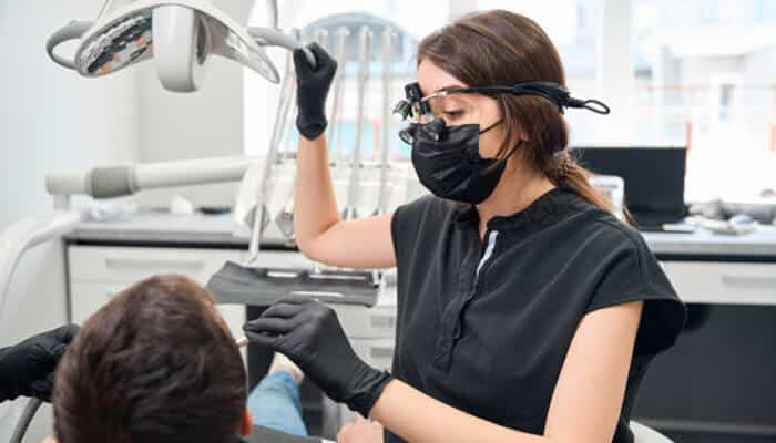 Dentist using dental loupes while performing a dental procedure on a patient in a modern dental clinic