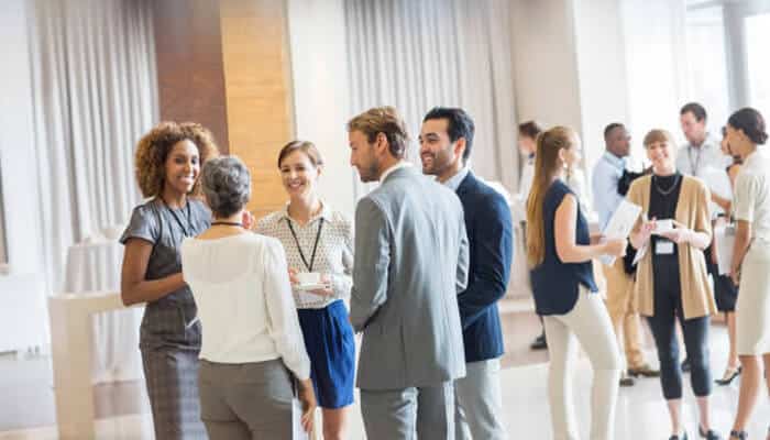 Young professionals networking at a corporate event, building connections that support a business management degree career path.