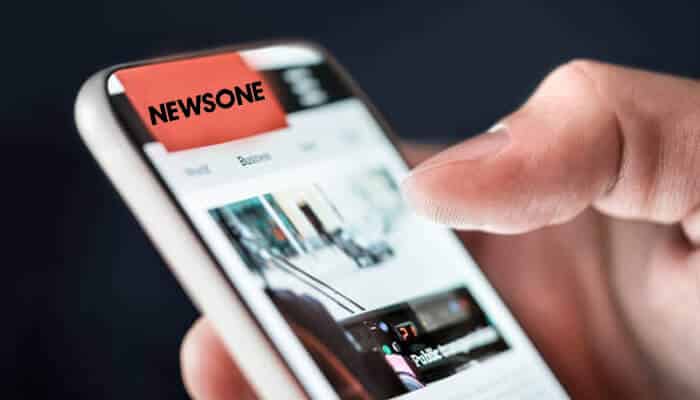A person scrolling through the newsone app on a smartphone, illustrating digital news consumption in a story referencing rashad robinson and media coverage on social issues.