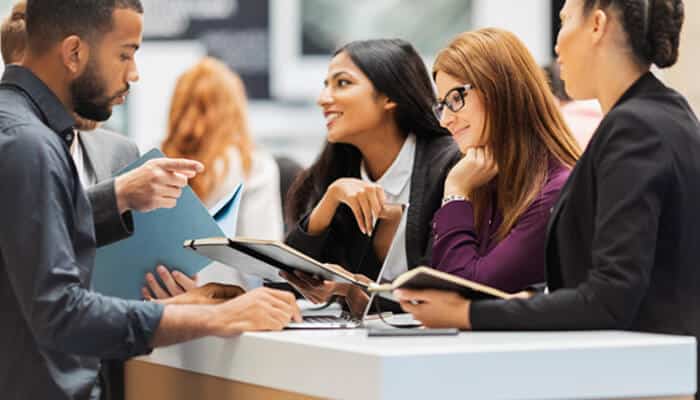 Professionals networking and discussing ideas at a booth during hr conferences, sharing notes and insights on workplace trends and talent management.