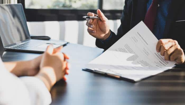 Negotiation happens before the application is filed | tycoonstory media A person discusses documents with a lawyer during a consultation, likely related to land use and development approvals, highlighting the importance of legal guidance before filing applications.