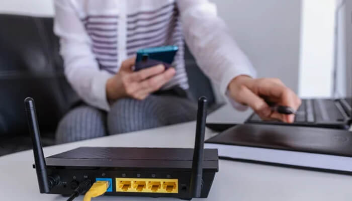 Wifi router with user managing connection on phone, representing home internet plans and smart device usage for efficient and reliable household connectivity