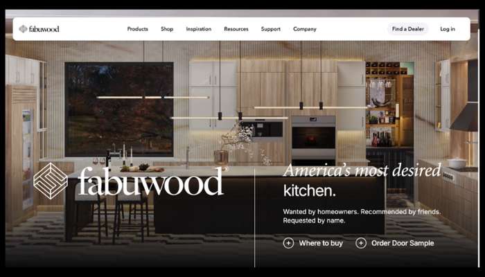 Modern kitchen showroom with light wood cabinetry, island, and pendant lights; fabuwood logo and 'america's most desired kitchen' slogan.