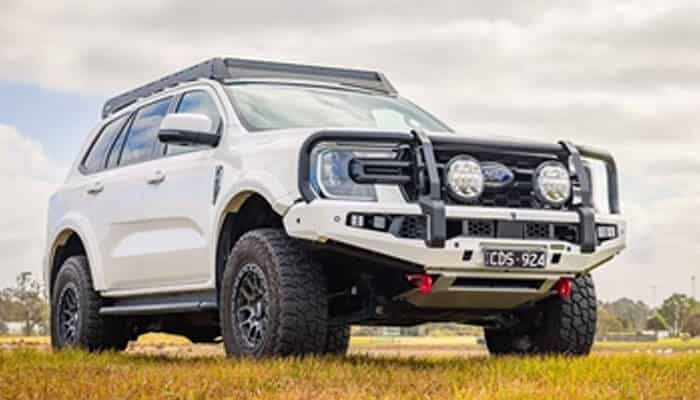 Key modifications to maximise business potential - tycoonstory | tycoonstory media White off-road suv with a heavy-duty bumper and roof rack parked on a grassy field, ready for adventure.