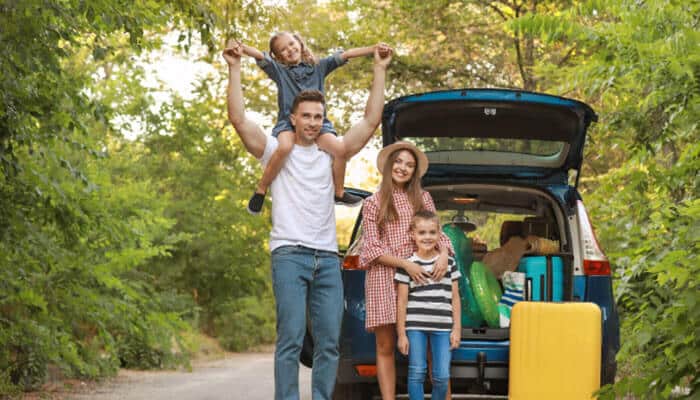 Kia telluride 2027 family road-trip scene with parents and children beside a packed suv, highlighting the three-row telluride’s family-focused seating and cargo versatility.