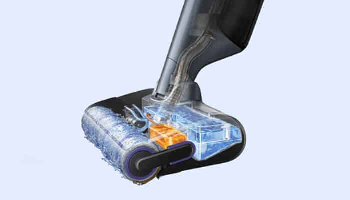 Close-up of a cordless vacuum cleaner head with a rotating brush and transparent dust chamber.
